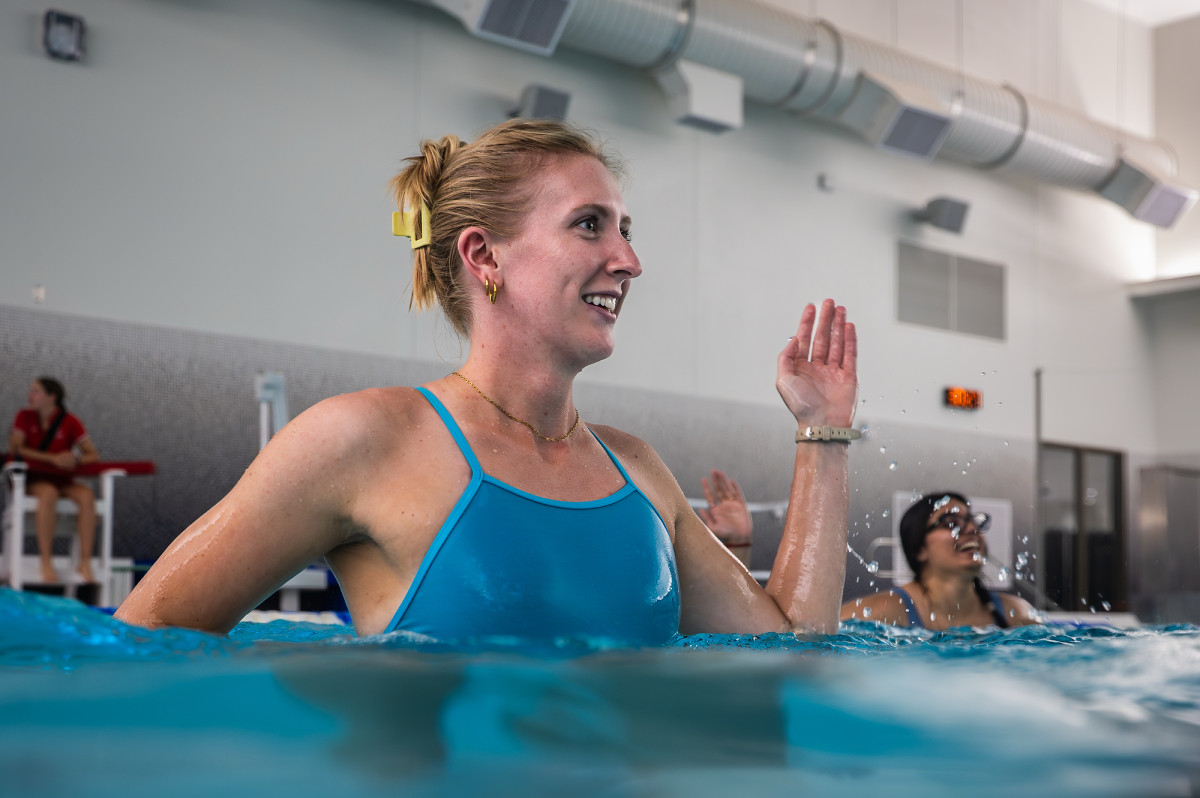 Close view of one student smiling as she raises one hand while following the instructor