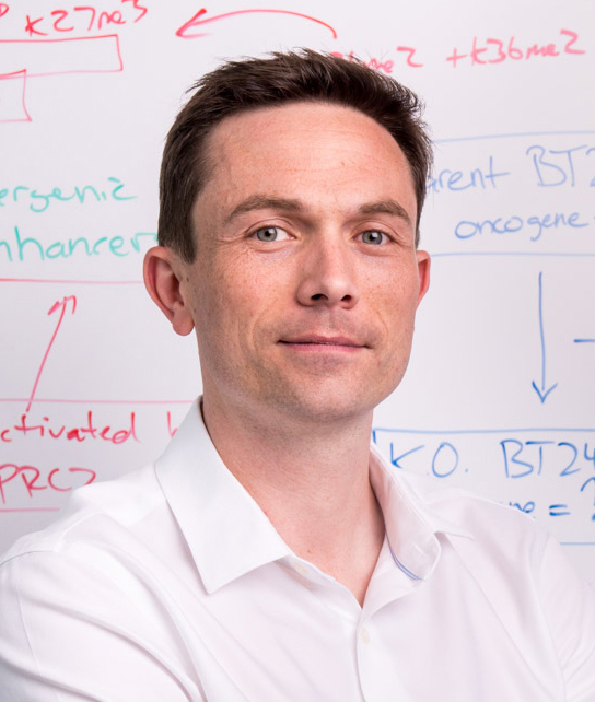 Headshot of researcher Peter Lewis, with a whiteboard in the background. 