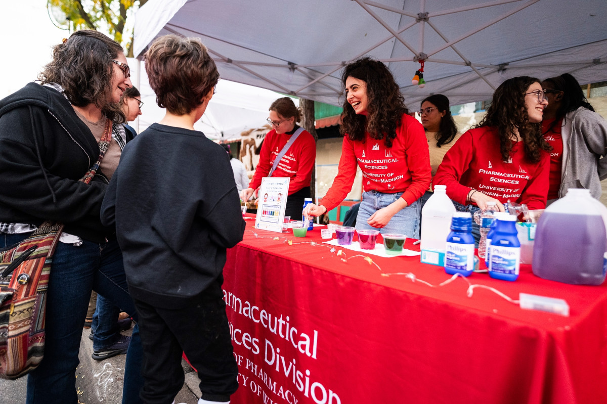 Pharmacy students speak with members of the public at a display booth.
