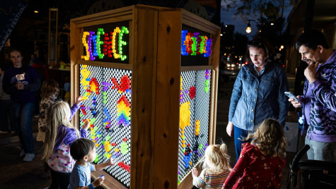 Parents and young children interact with a colorful light display board