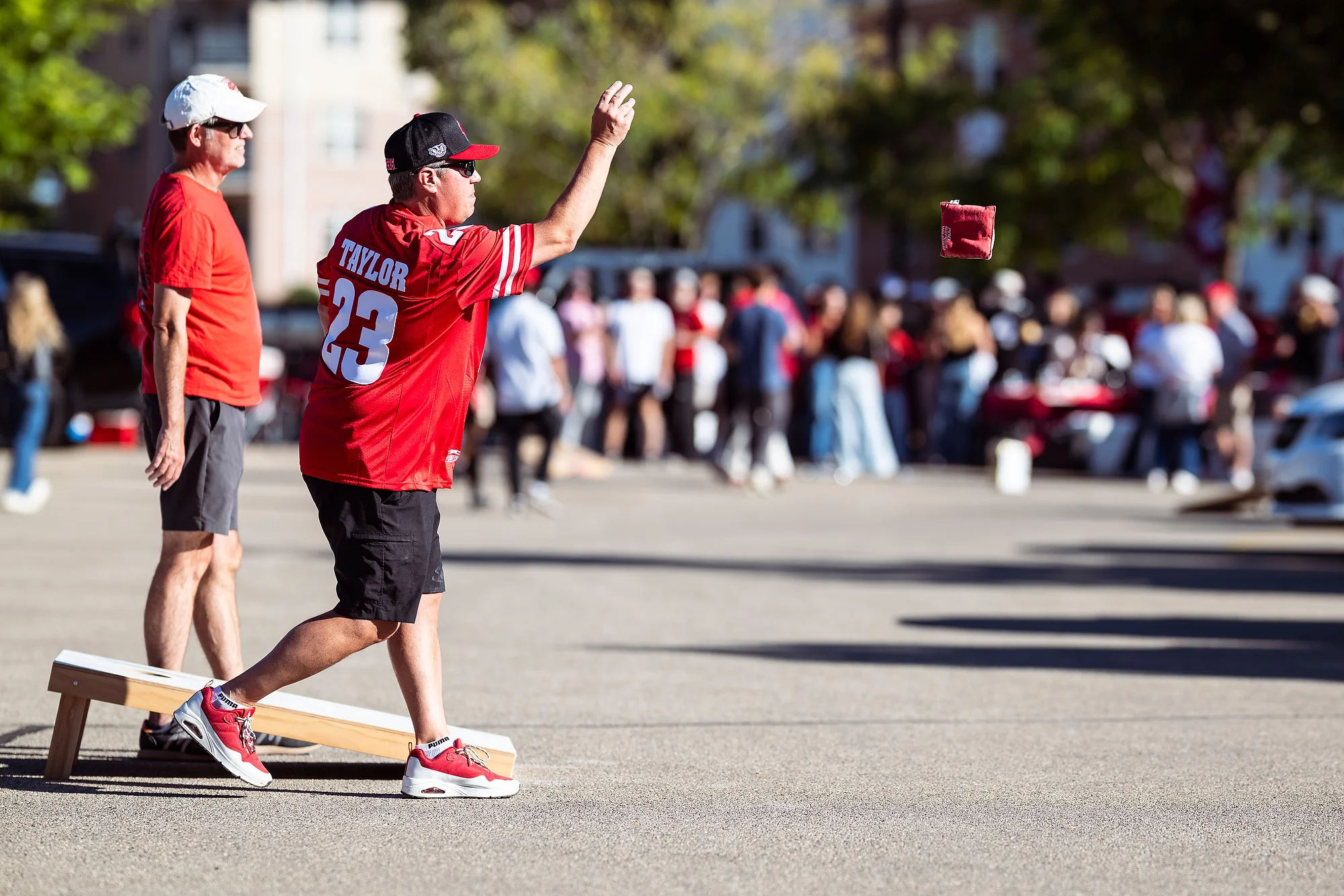 Badger fans wearing red play bean bag toss in a parking lot