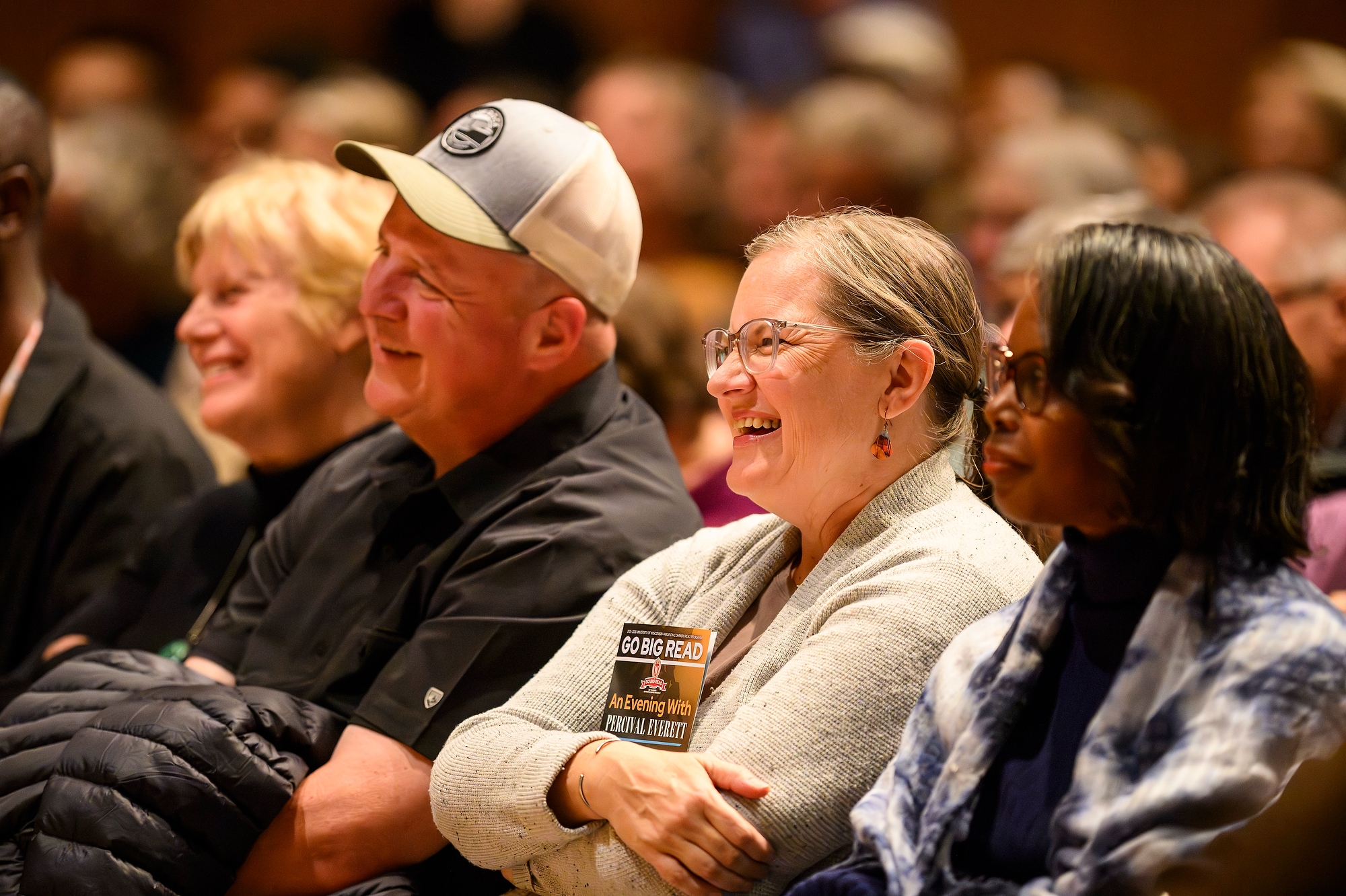 A group of people sitting in an auditorium smile and laugh.