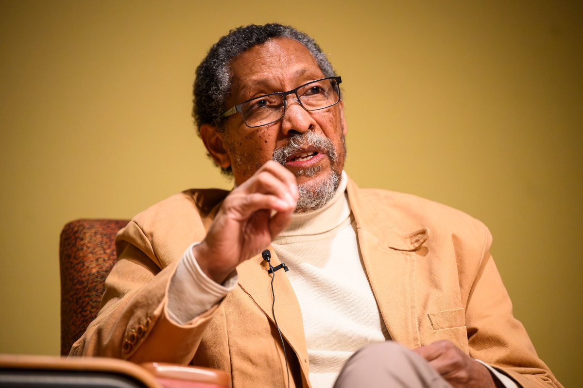 A man sitting in a chair gestures as he talks.
