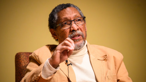 A man sitting in a chair gestures as he talks.