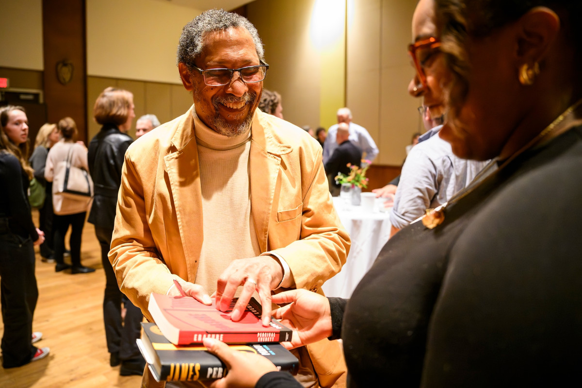 A man smiles and accepts a book from a woman.