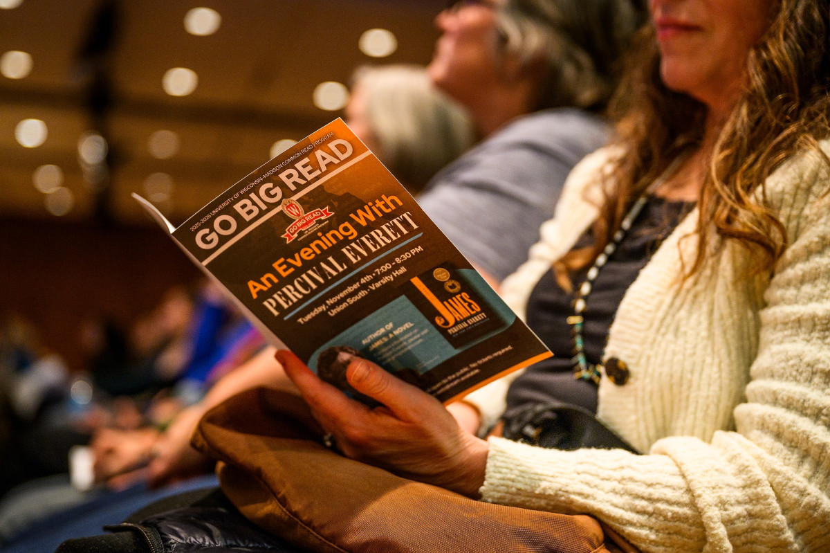 Someone holds a program as they sit in an audience in an auditorium.