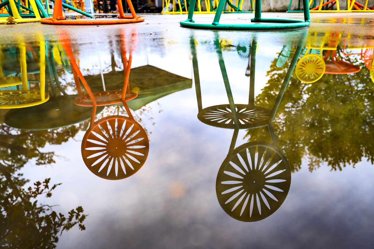 Reflection of colorful chairs in a puddle of water