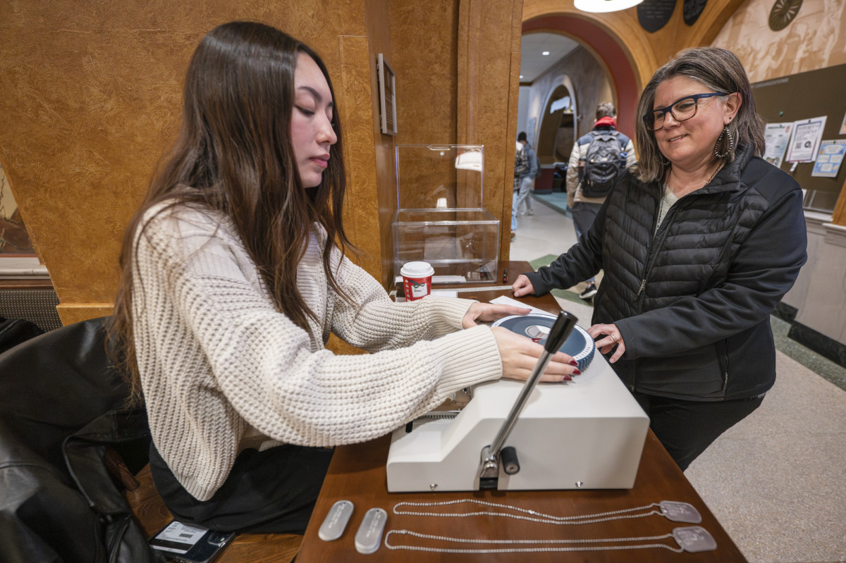 A woman waits for a student to make a dog tag inside Memorial Union.