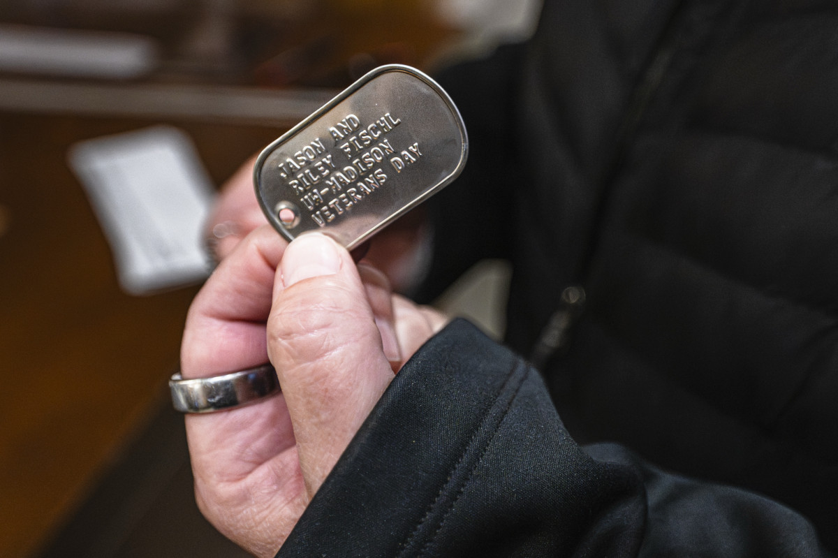 A close up of a hand holding a metal dog tag.