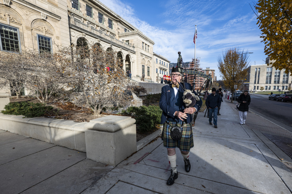 A man plays a bagpipe and walks up Langdon Street outside of Memorial Union.