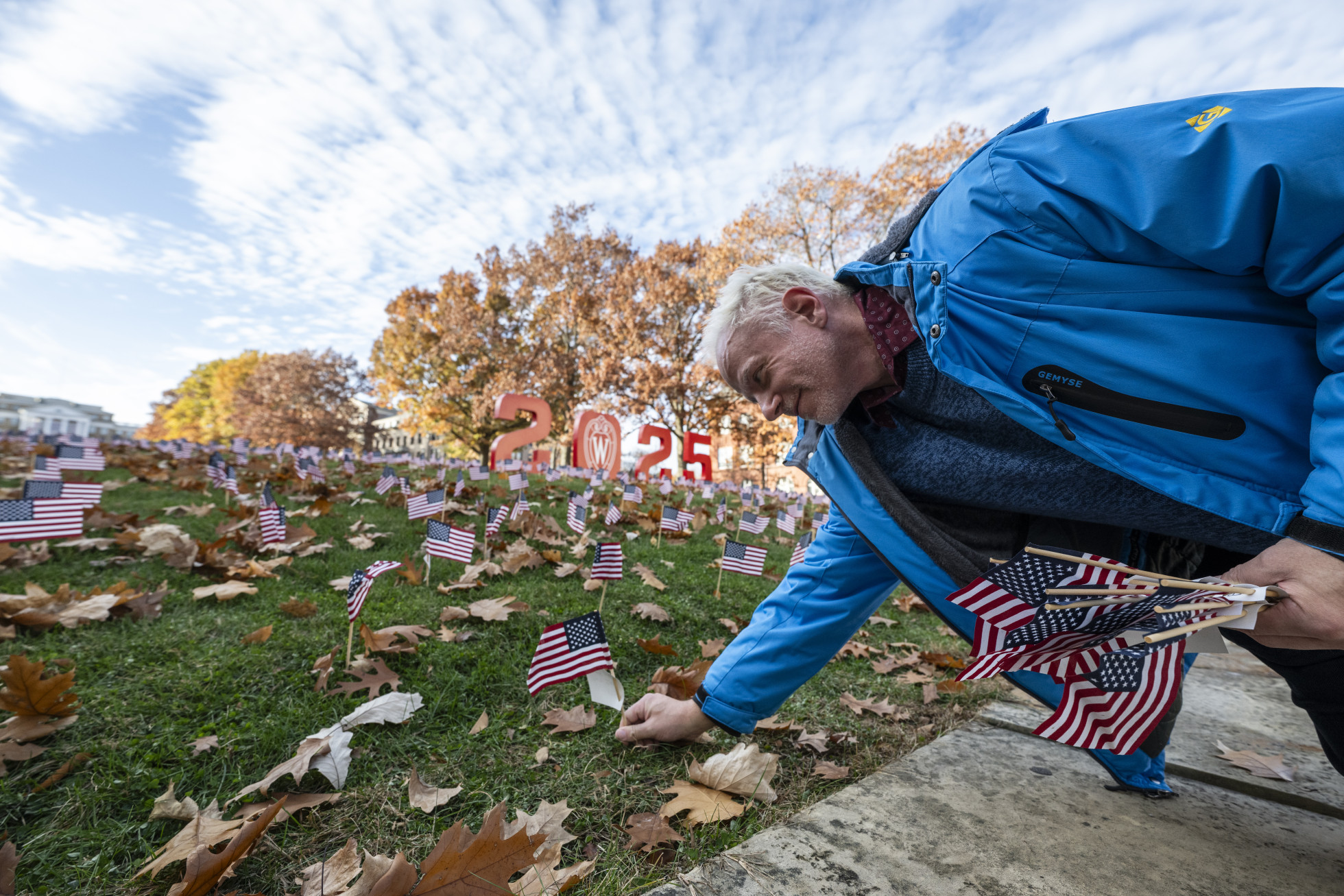 A man places a flag in the ground on Bascom Hill.