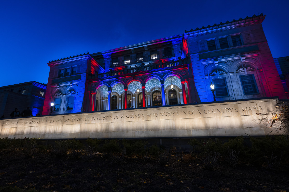 An exterior image of the UW Memorial Union lit up with red and blue lights.