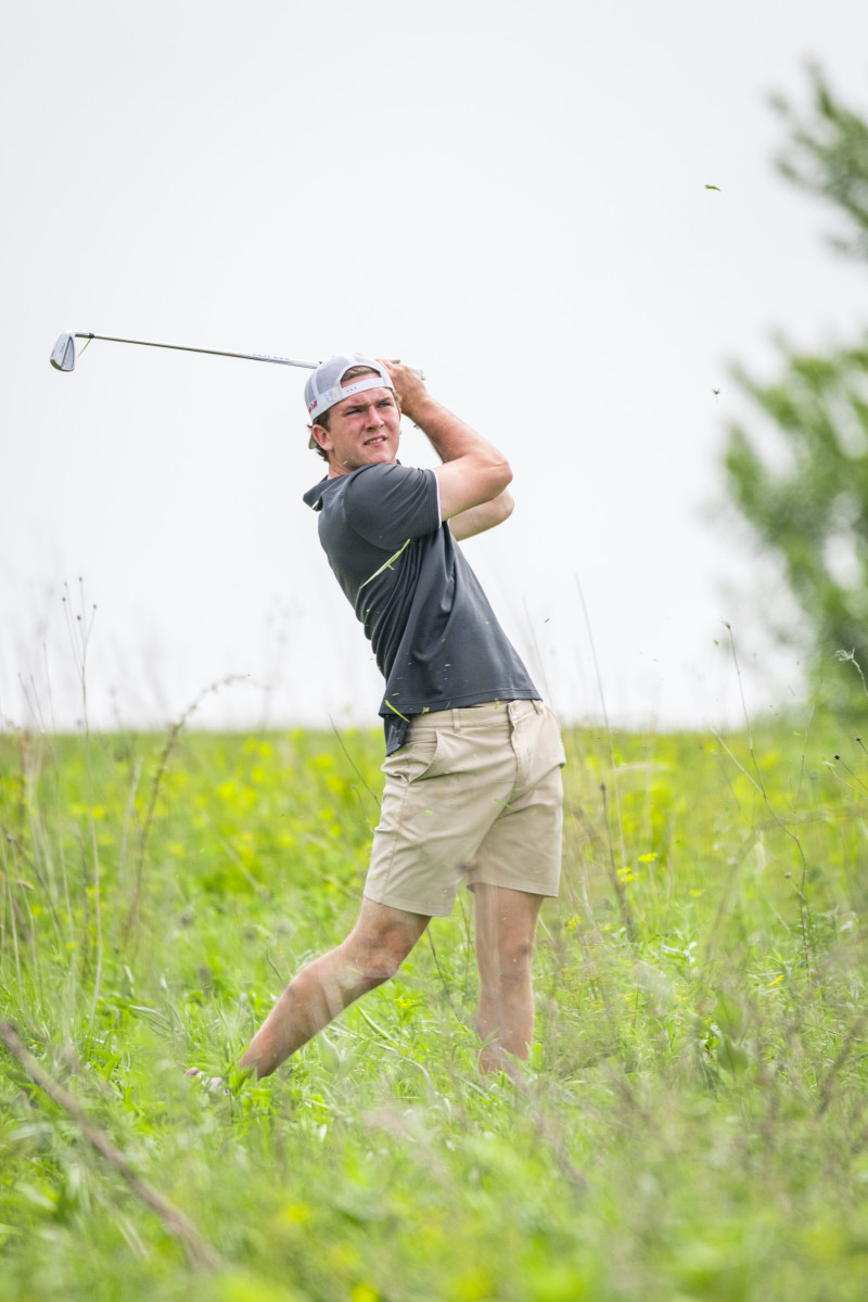 A young man follows through with his golf swing.