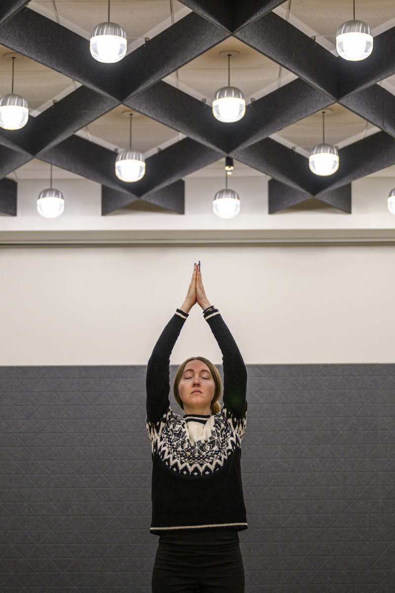 A person meditating with eyes closed and their hands meeting above their head