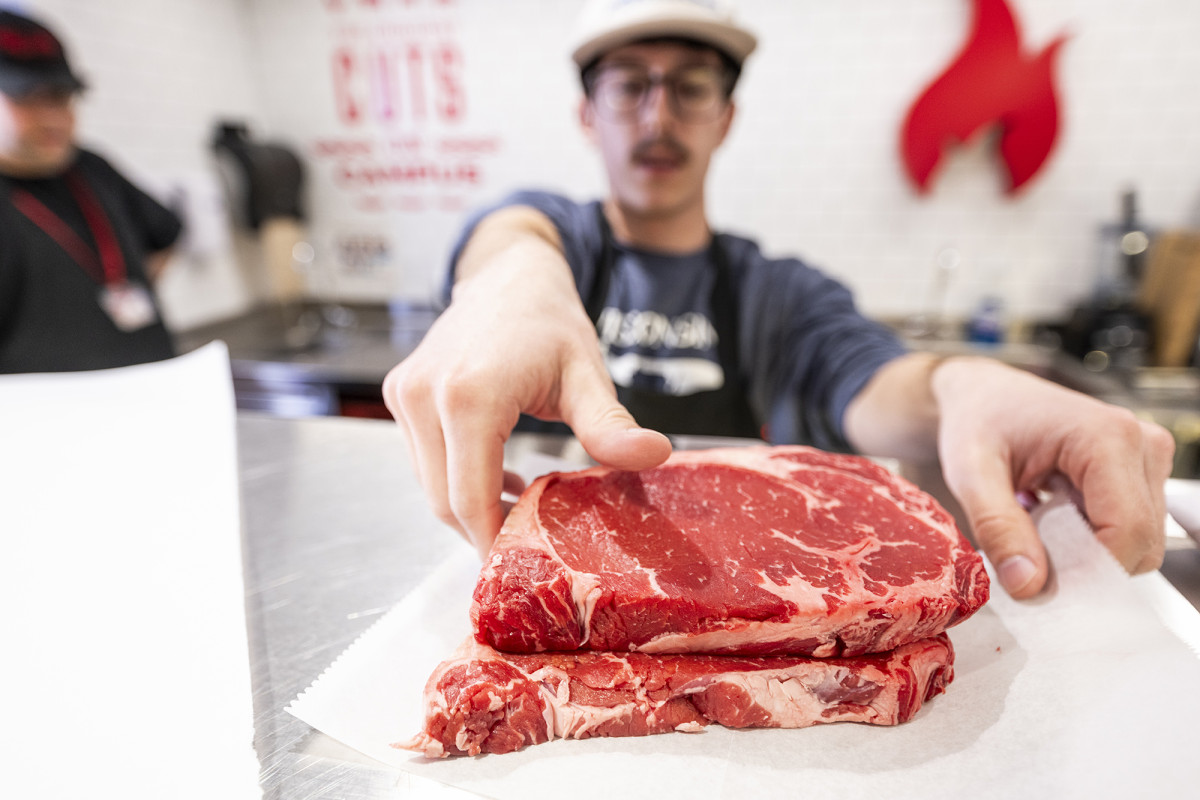 A person placing a cut of red meat on a piece of butcher paper