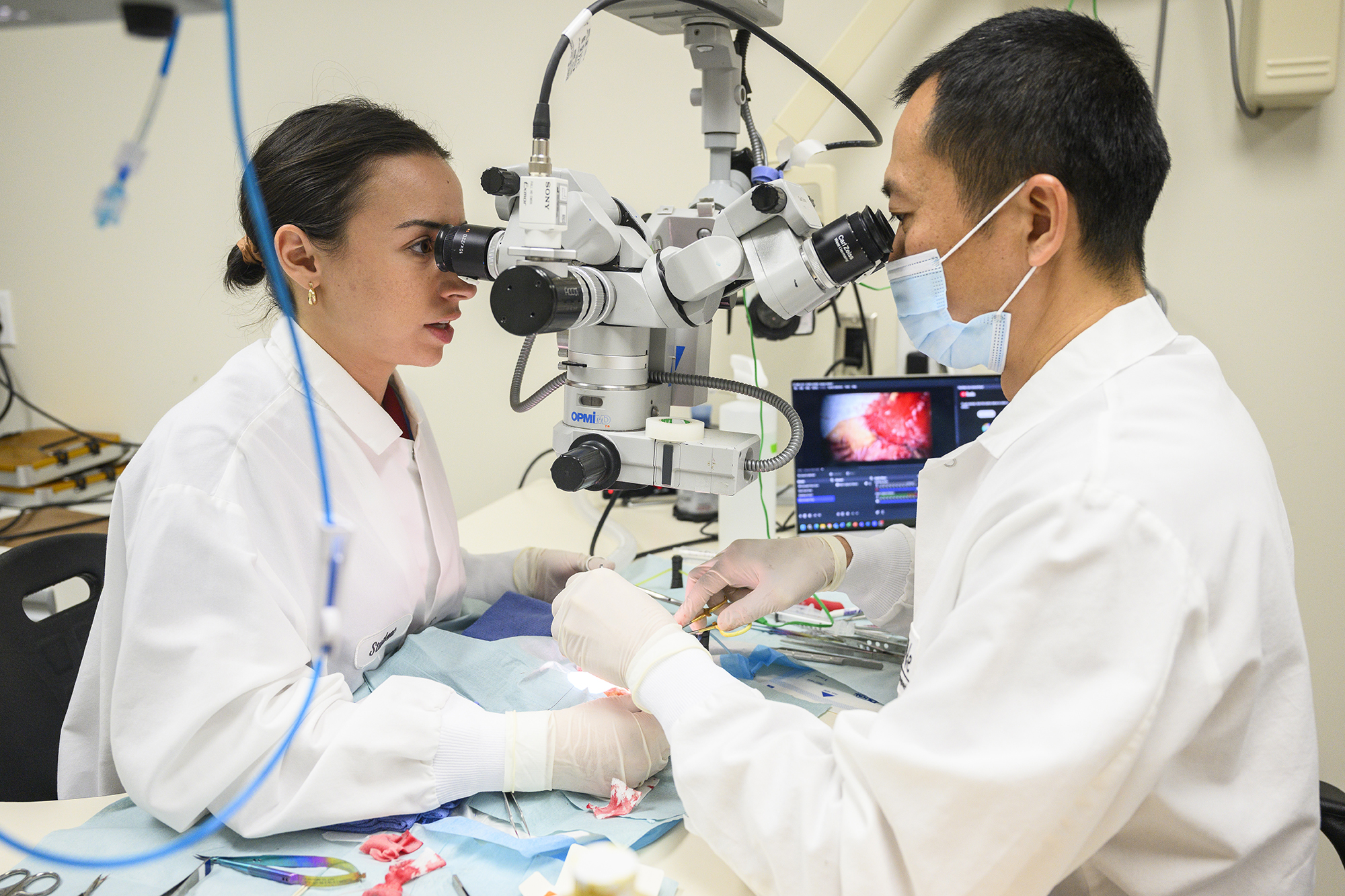 Two medical professionals using tools to perform a surgery