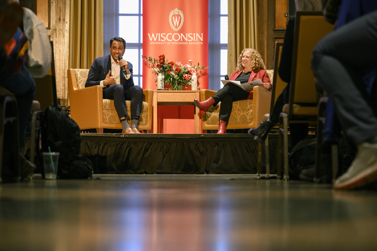 Two people sitting on a stage speaking to a group