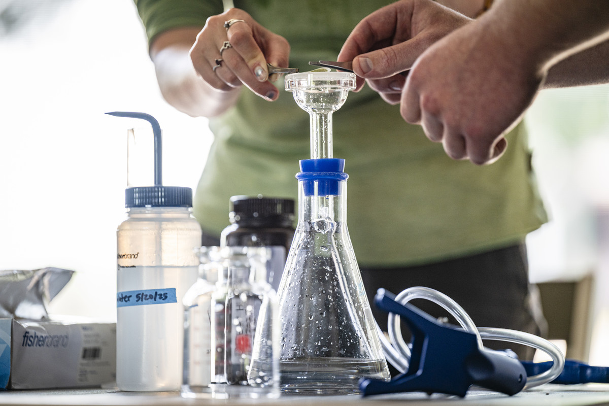 Close-up of hands holding tweezers over an Erlenmeyer Flask