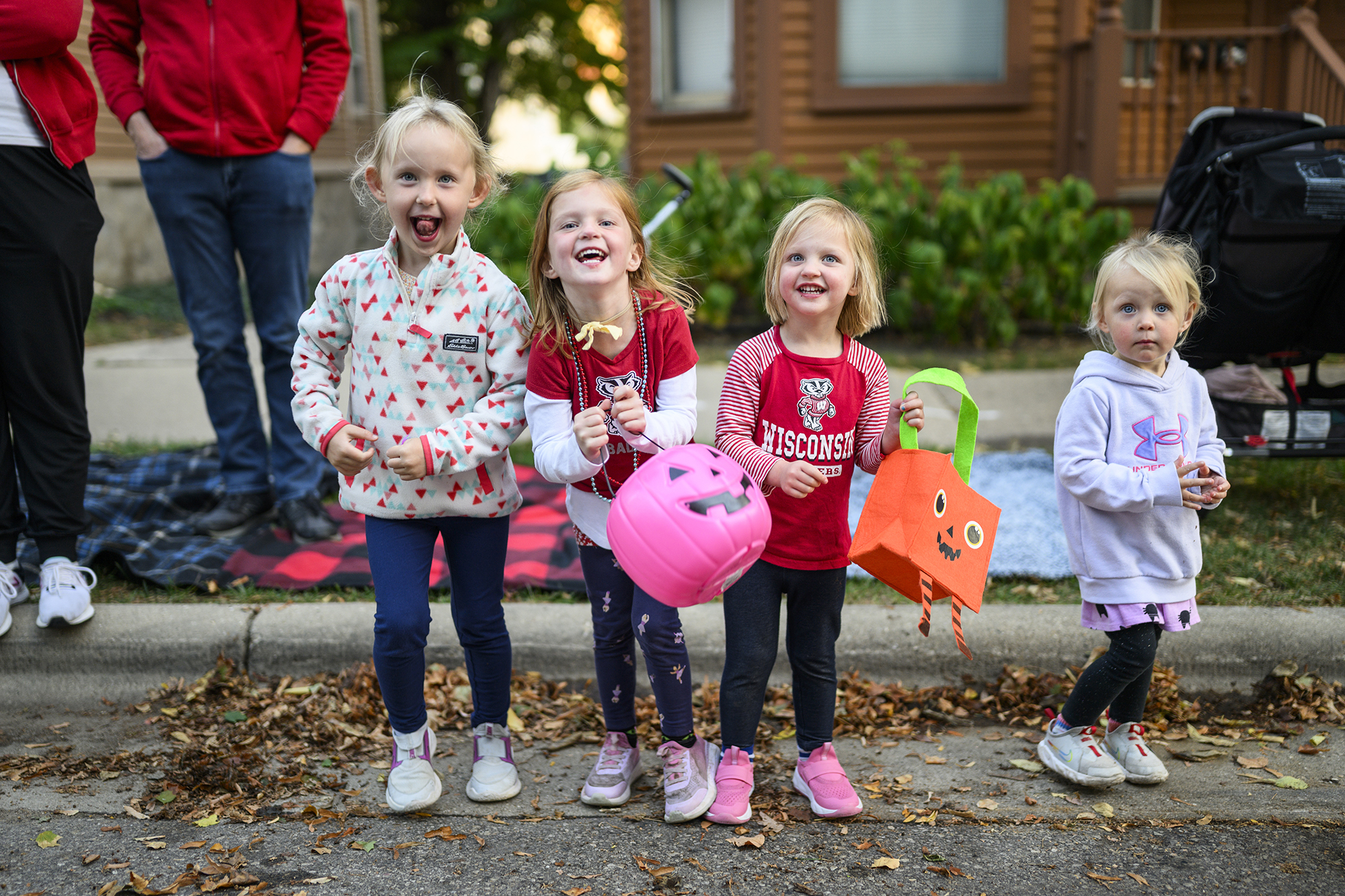 Four young children holding Halloween candy bags and smiling at the camera