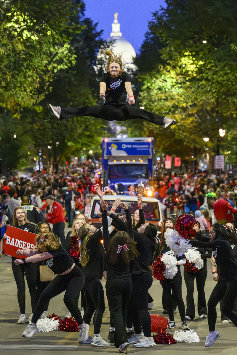 A parade with a group of cheerleaders throwing one cheerleader into the air