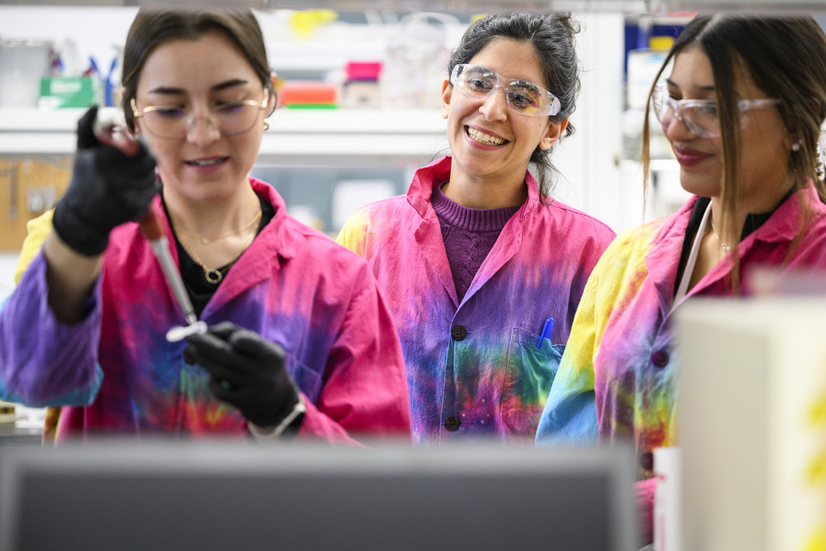 Three smiling scientists wearing tie-dyed lab coats