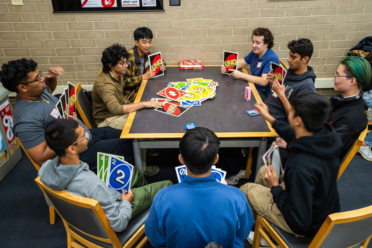 A group of students playing a card game around a table