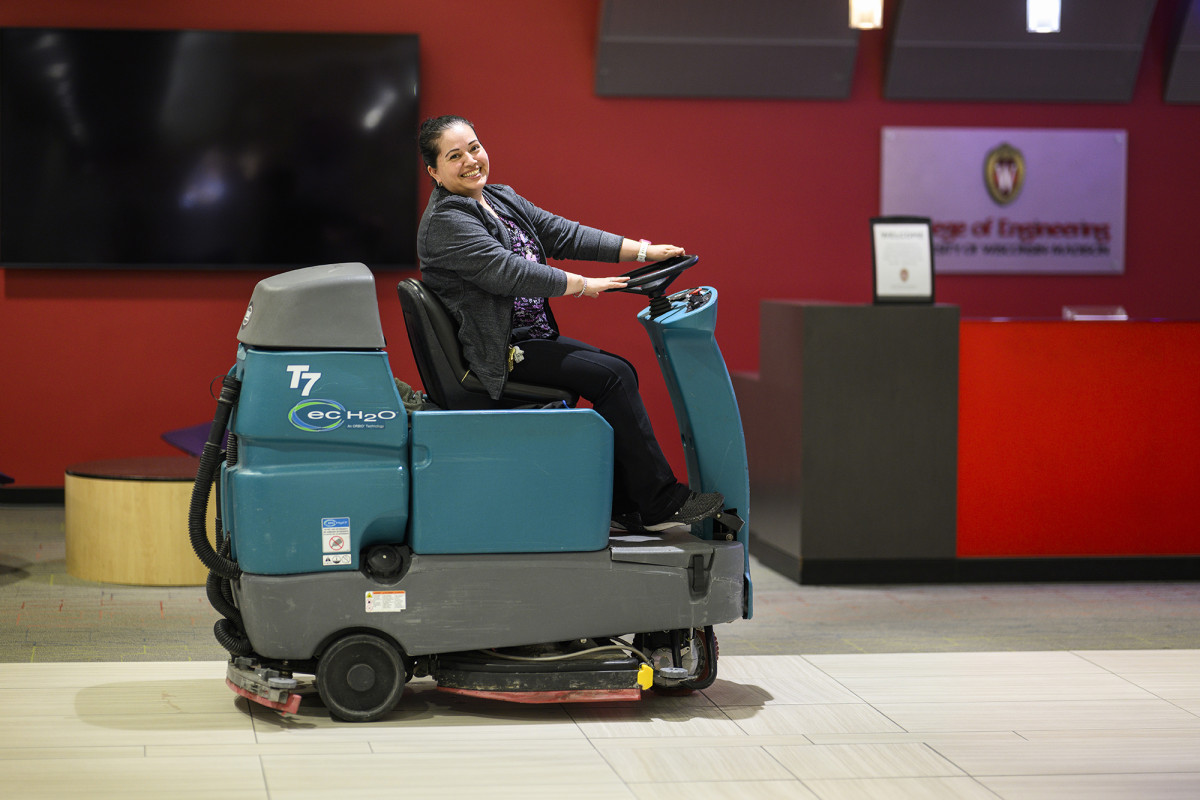 A person driving an industrial floor cleaning machine