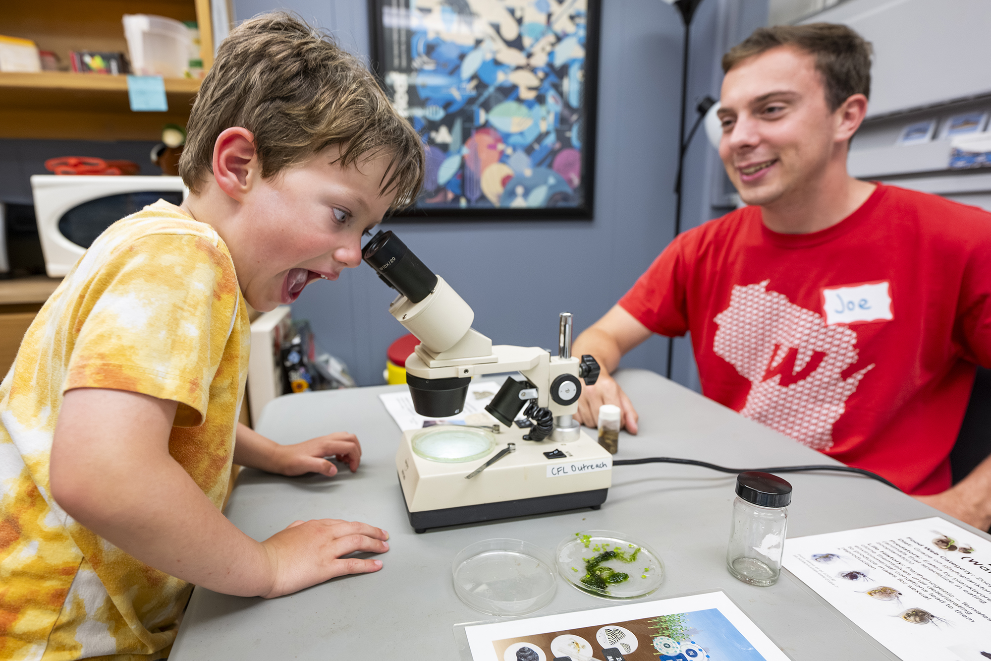 An excited child looking into a microscope