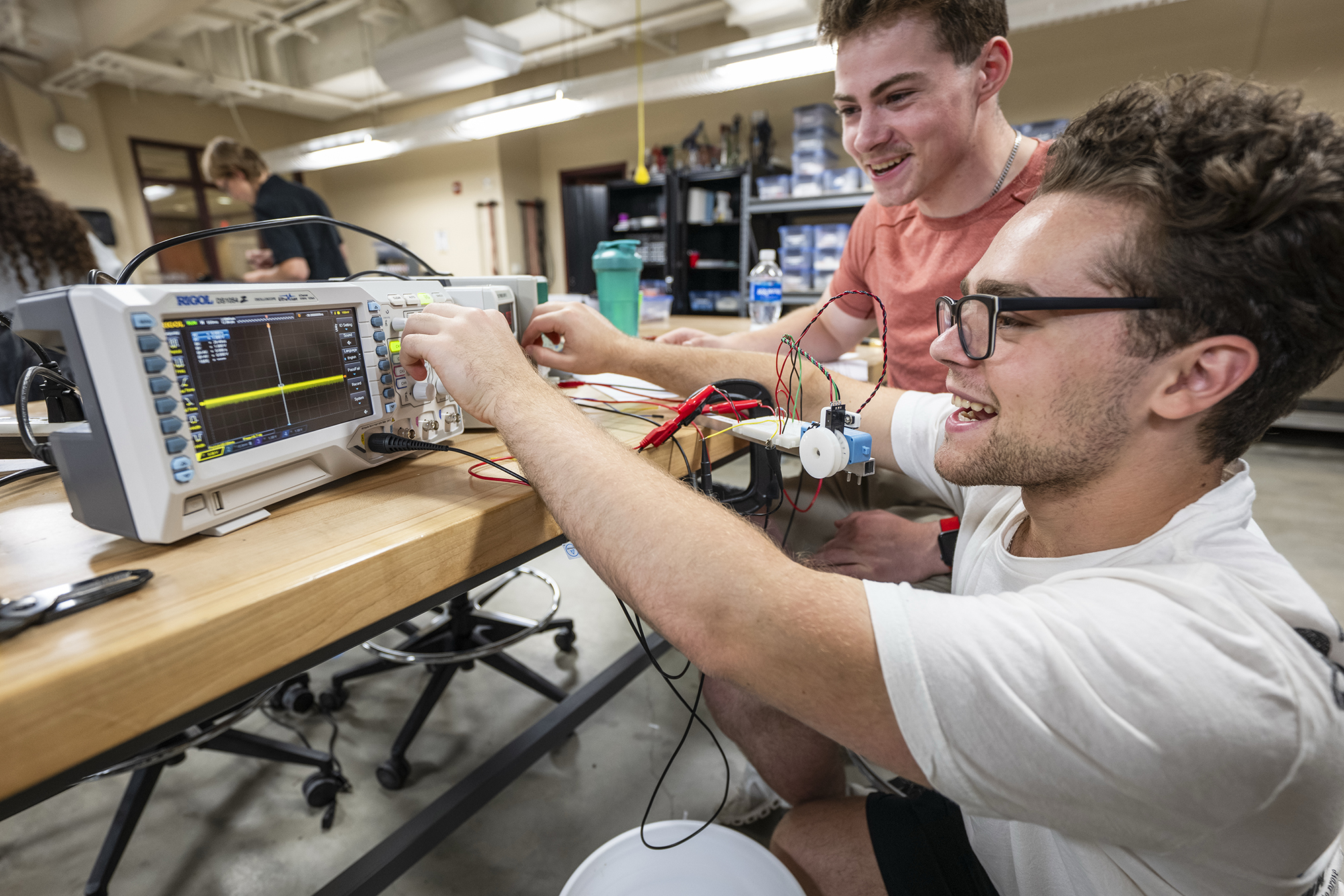 Two smiling students working with electronics