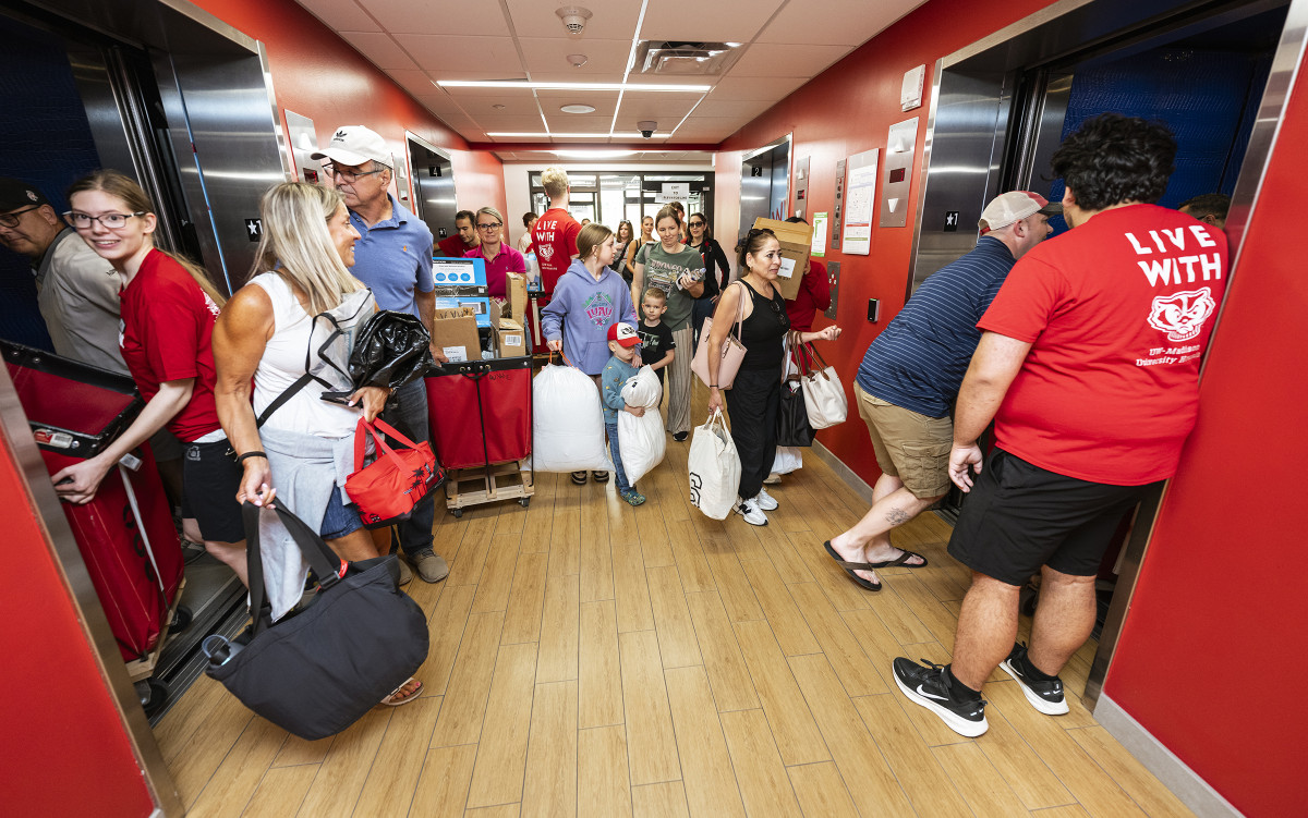 Groups of people with moving carts entering elevators