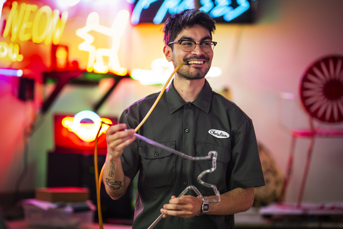 A smiling person while creating a neon sculpture