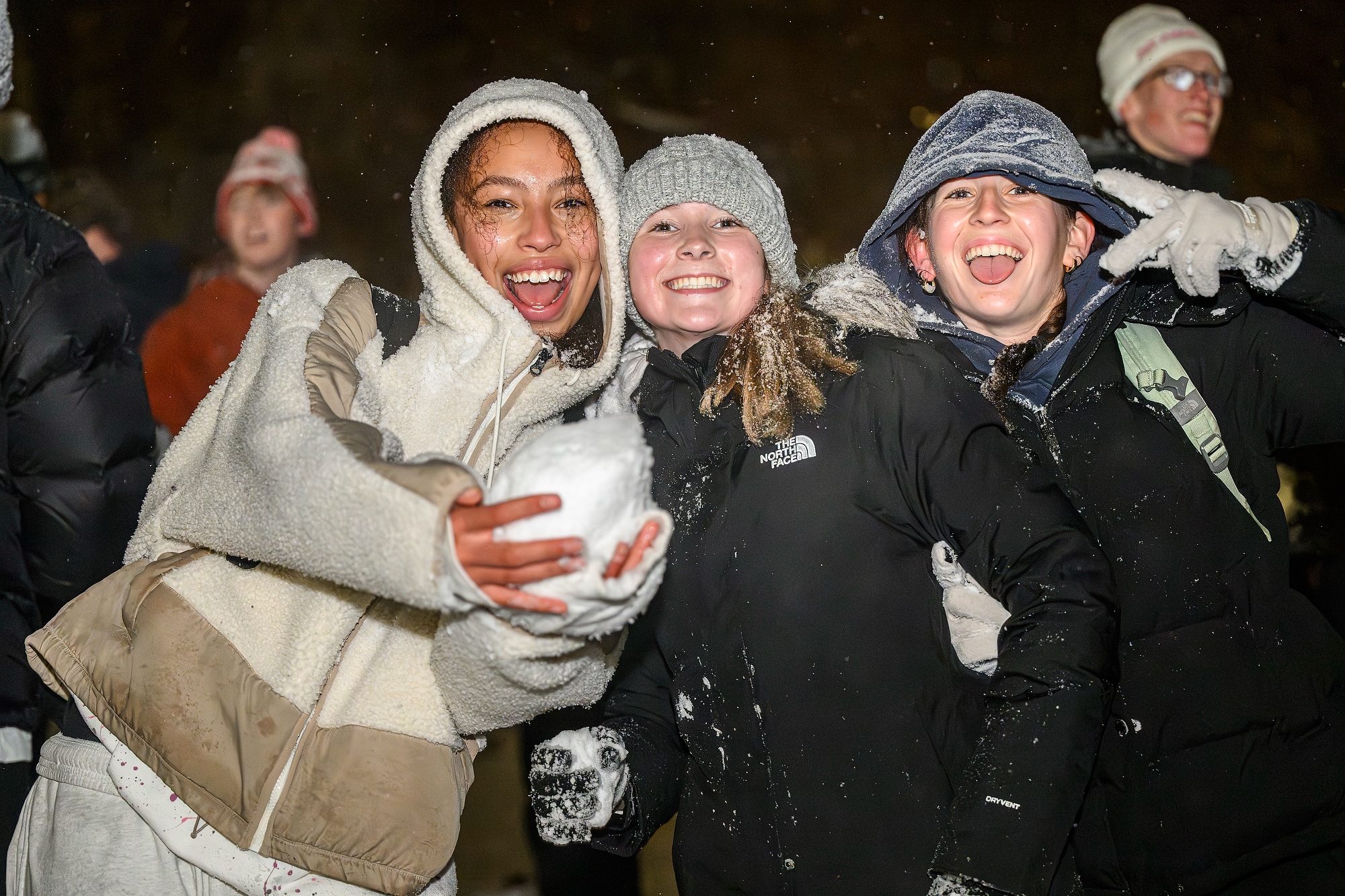 Three students, one holding a giant snowball, smiling for a photo