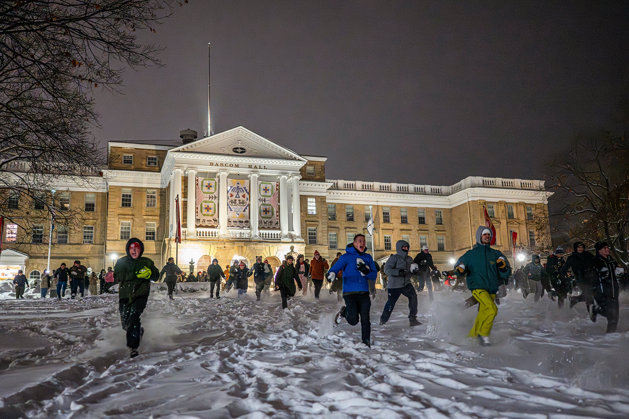Dozens of students running down Bascom Hill holding snowballs.