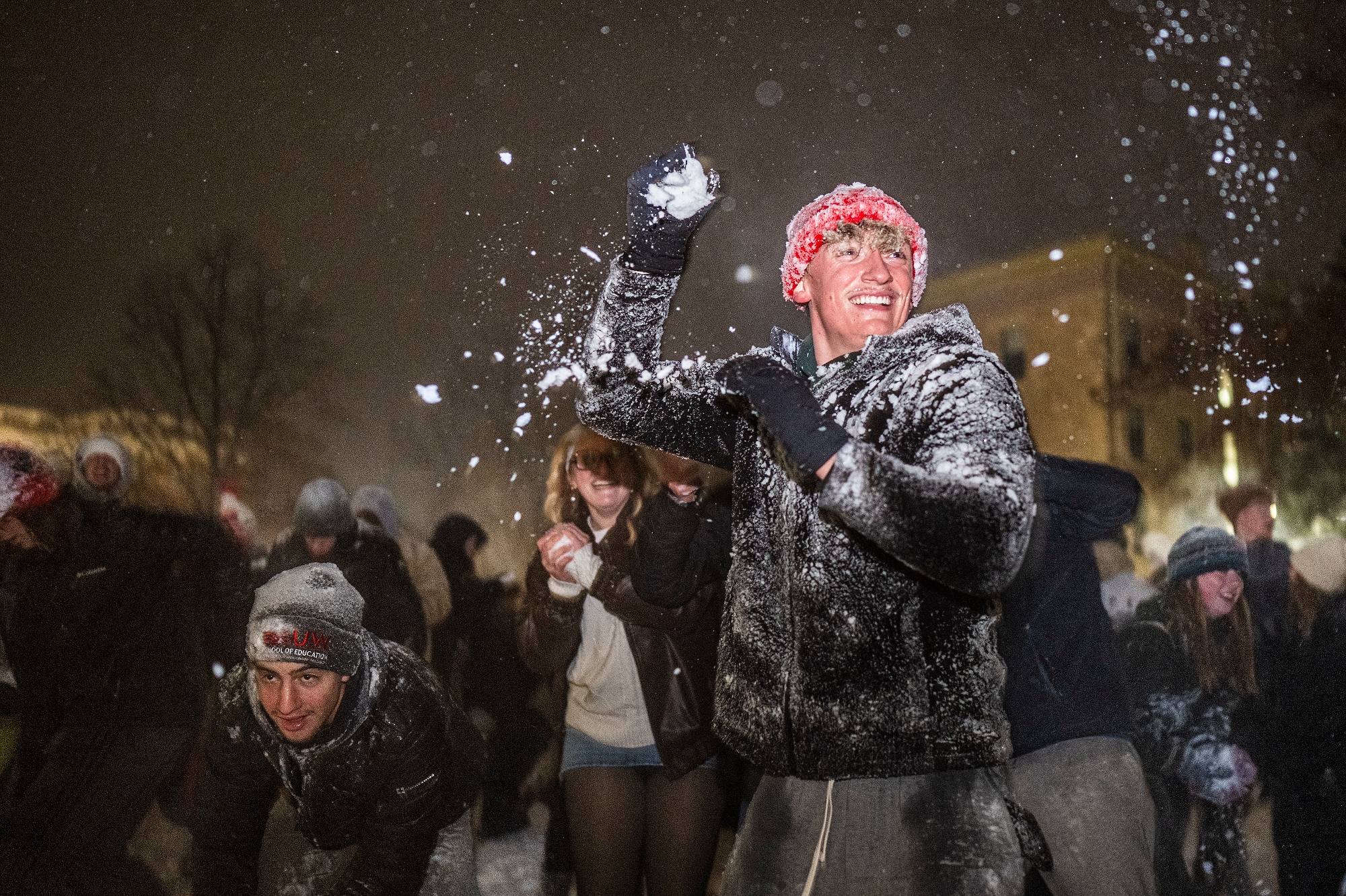 Student in a red hat throwing a snowball