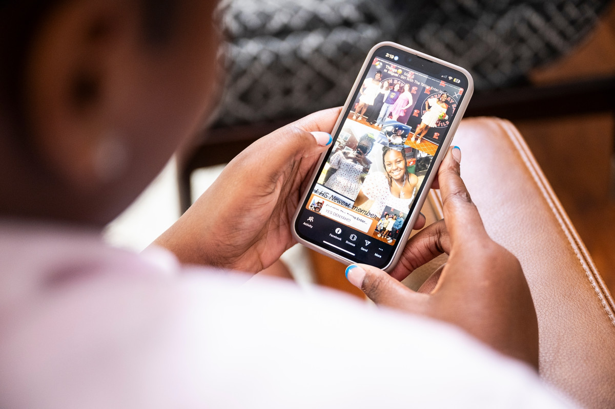 A view of a social media app on a phone over the shoulder of a young woman