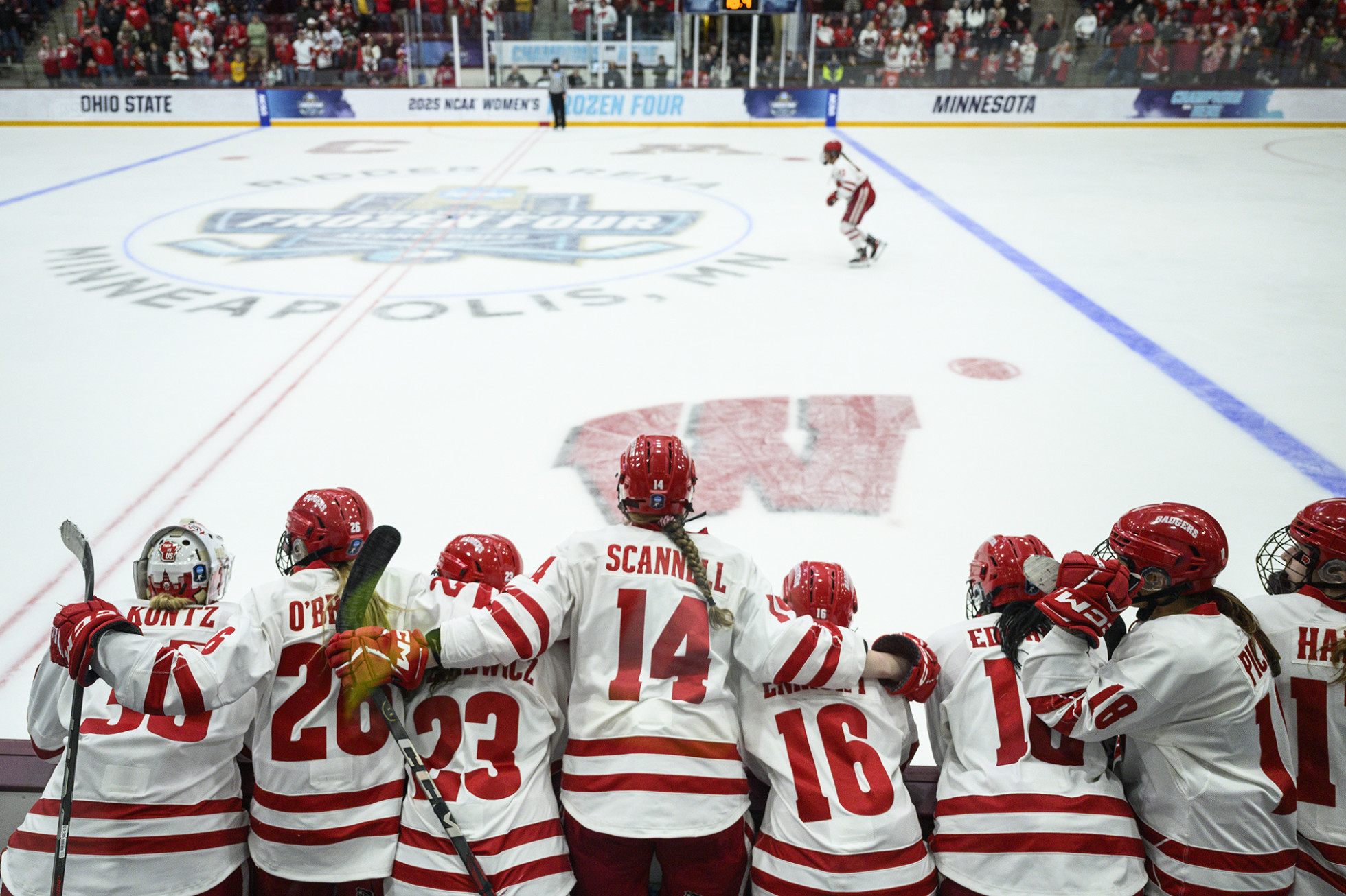 Single hockey player on the ice with their teammates watching from the sidelines