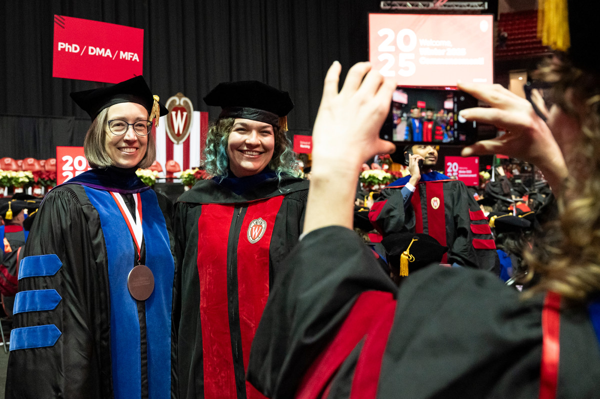 A professor and her graduating advisee smile and stand for a photo.