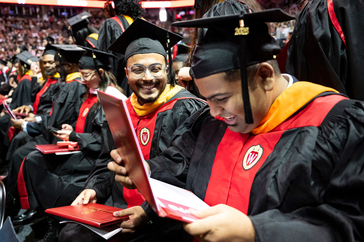 Graduates smiling while looking at diploma