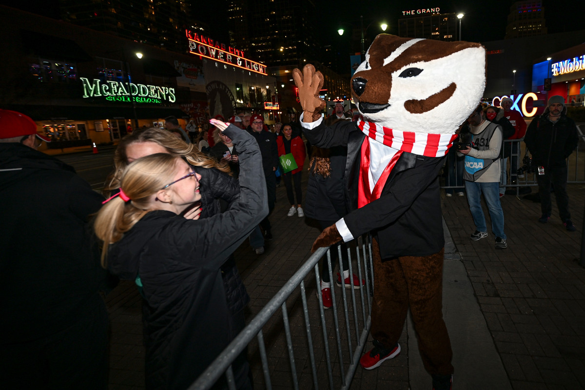 Bucky Badger, wearing a tuxedo, high fives a girl outside T-Mobile Center.