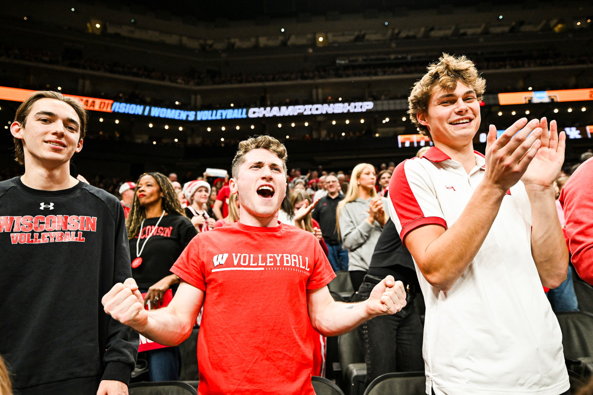 A trio of Badger fans pump their fists and clap their hands during the match.