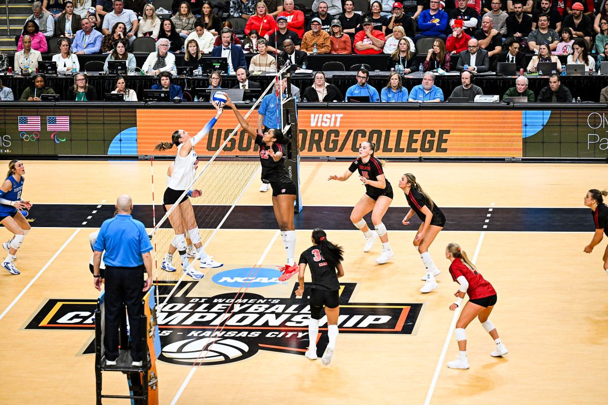 Volleyball players Carter Booth and Eva Hudson jump and meet at the net. 
