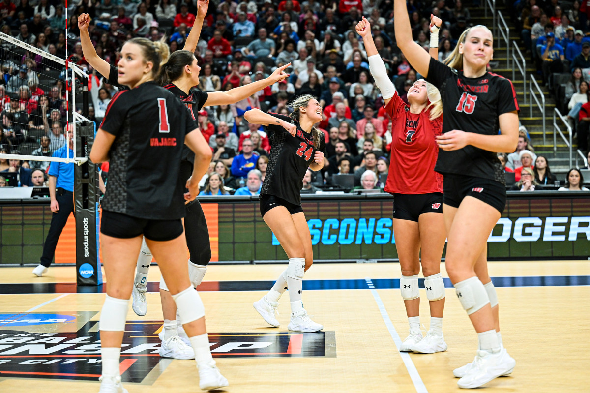 Badger volleyball players pump their fists and rasie their hands in celebration.