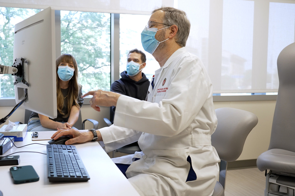 Dr. Dixon Kaufman gestures at a computer screen as Shawn Wiederhoeft and his sister Megan look on