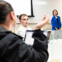 Wichowsky stands at the front of the classroom and listens to a student speaking during the class.