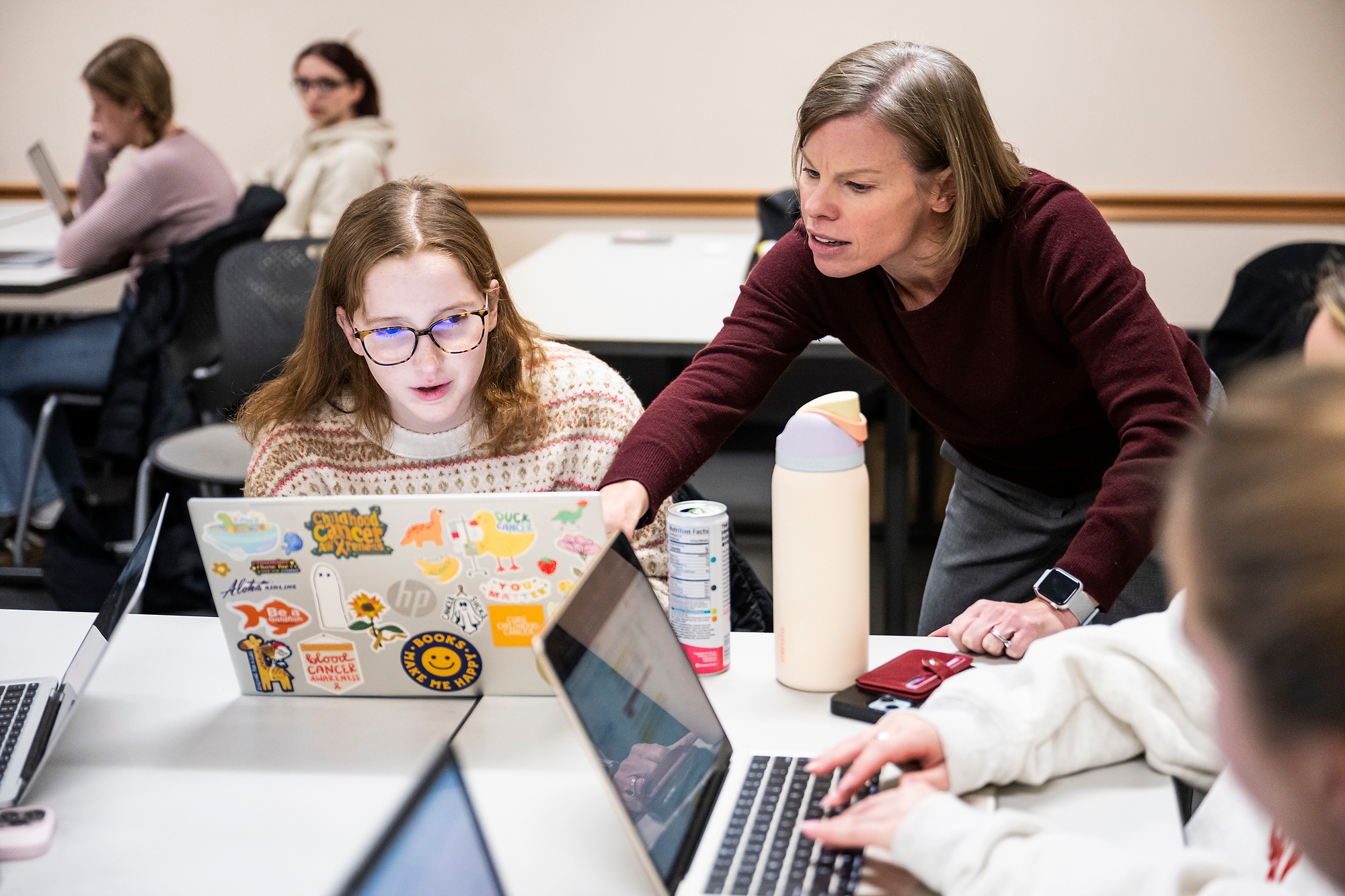 Wichowsky leans over a seated Sciara as both reference something on Sciara's computer screen.