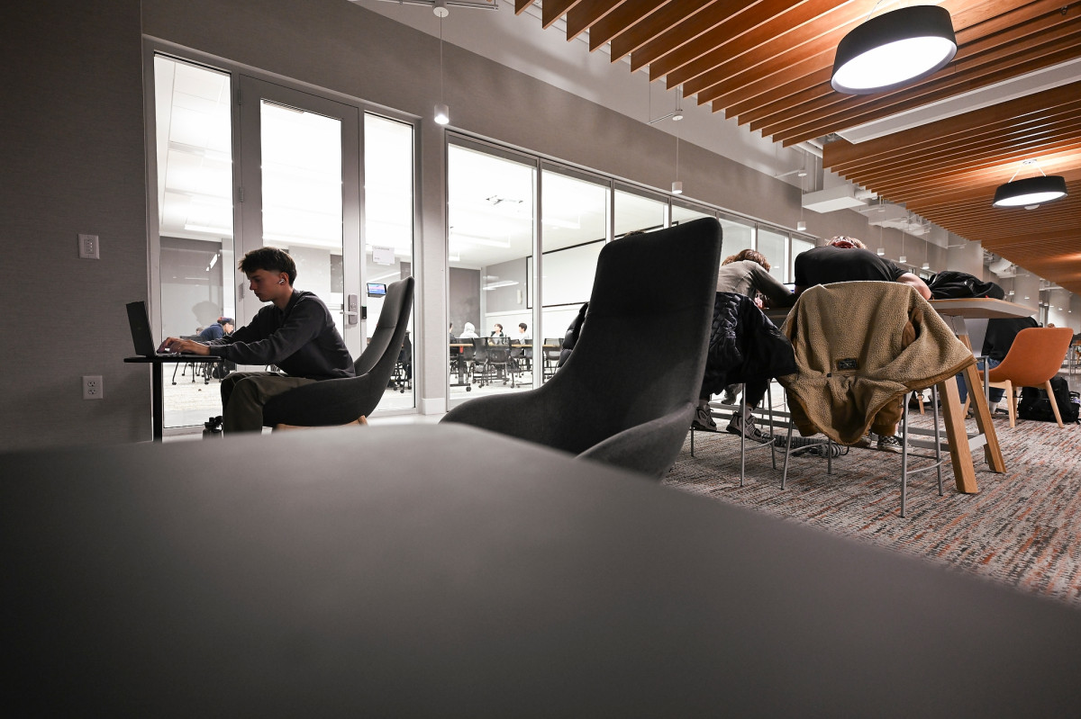 A student sits in a quiet corner of a study space and works on his laptop.