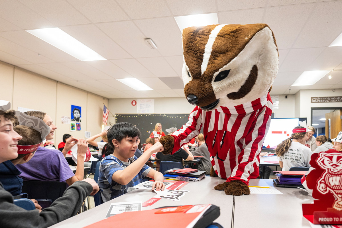 The Bucky Badger mascot does a fist bump with a student in a seventh-grade classroom 