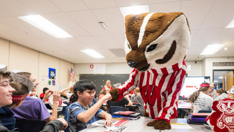 The Bucky Badger mascot does a fist bump with a student in a seventh-grade classroom