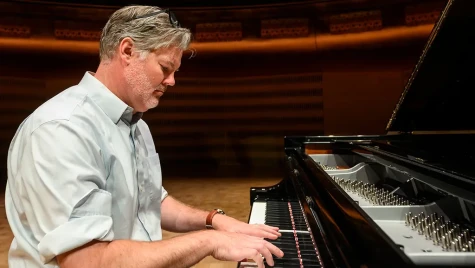 Cavanagh sits playing a piano.