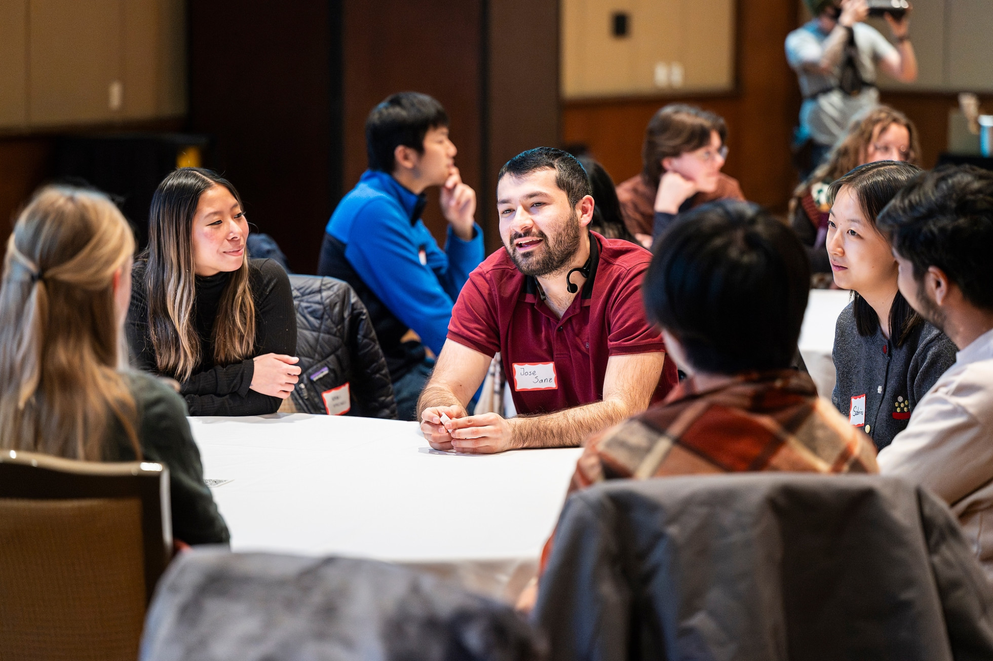 Community dinner participants sits around a table and discuss a topic prompt before dinner is served.
